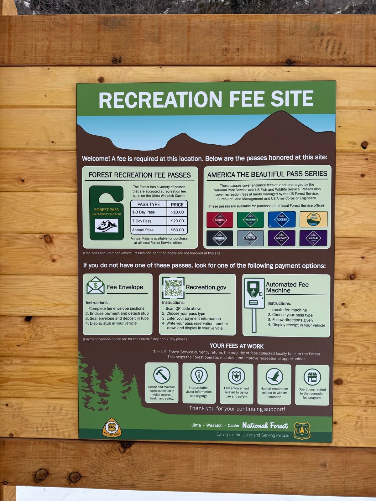 A sign at the Green Canyon recreation site in Utah outlining the required fees for access. It includes details about various passes, such as the Forest Recreation Pass and America the Beautiful Pass Series, along with their prices and instructions for payment options. The sign emphasizes the importance of the fees for maintaining the area and supporting recreational opportunities.