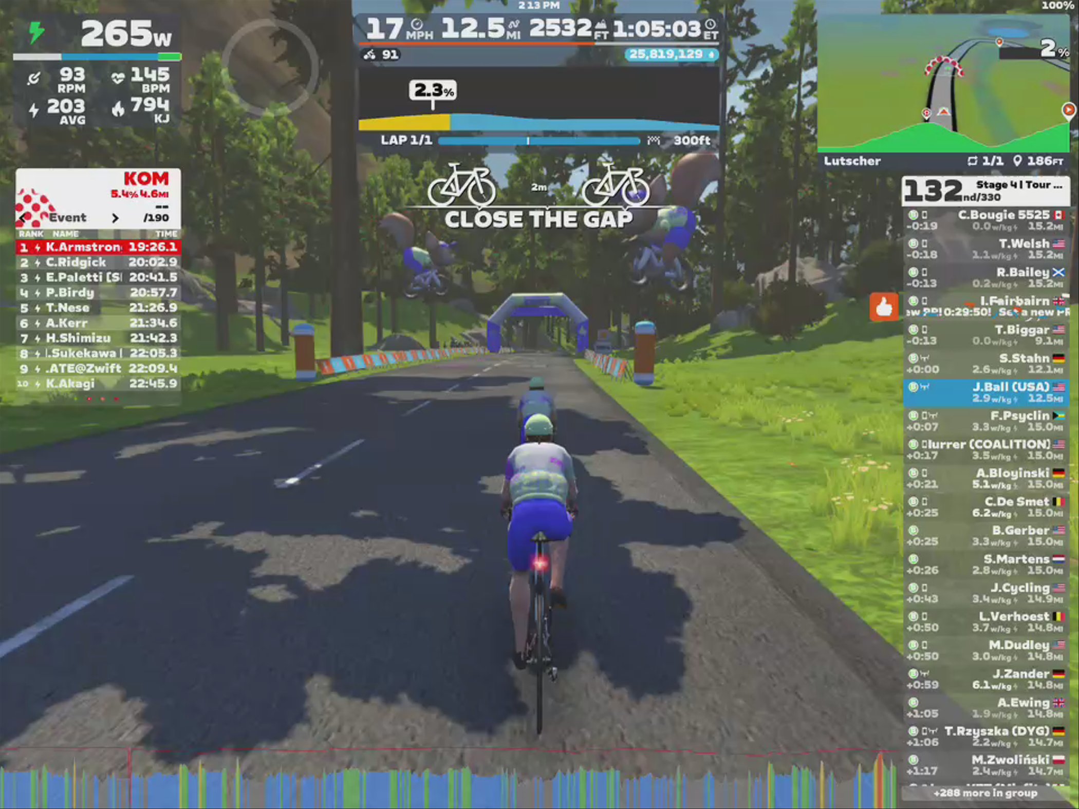 A cyclist in a virtual race environment on Zwift, navigating a scenic road surrounded by trees. The screen displays various performance metrics, including power output, speed, and heart rate. There is a leaderboard showing rankings and times of participants in the event, along with a map indicating the cyclist's progress.