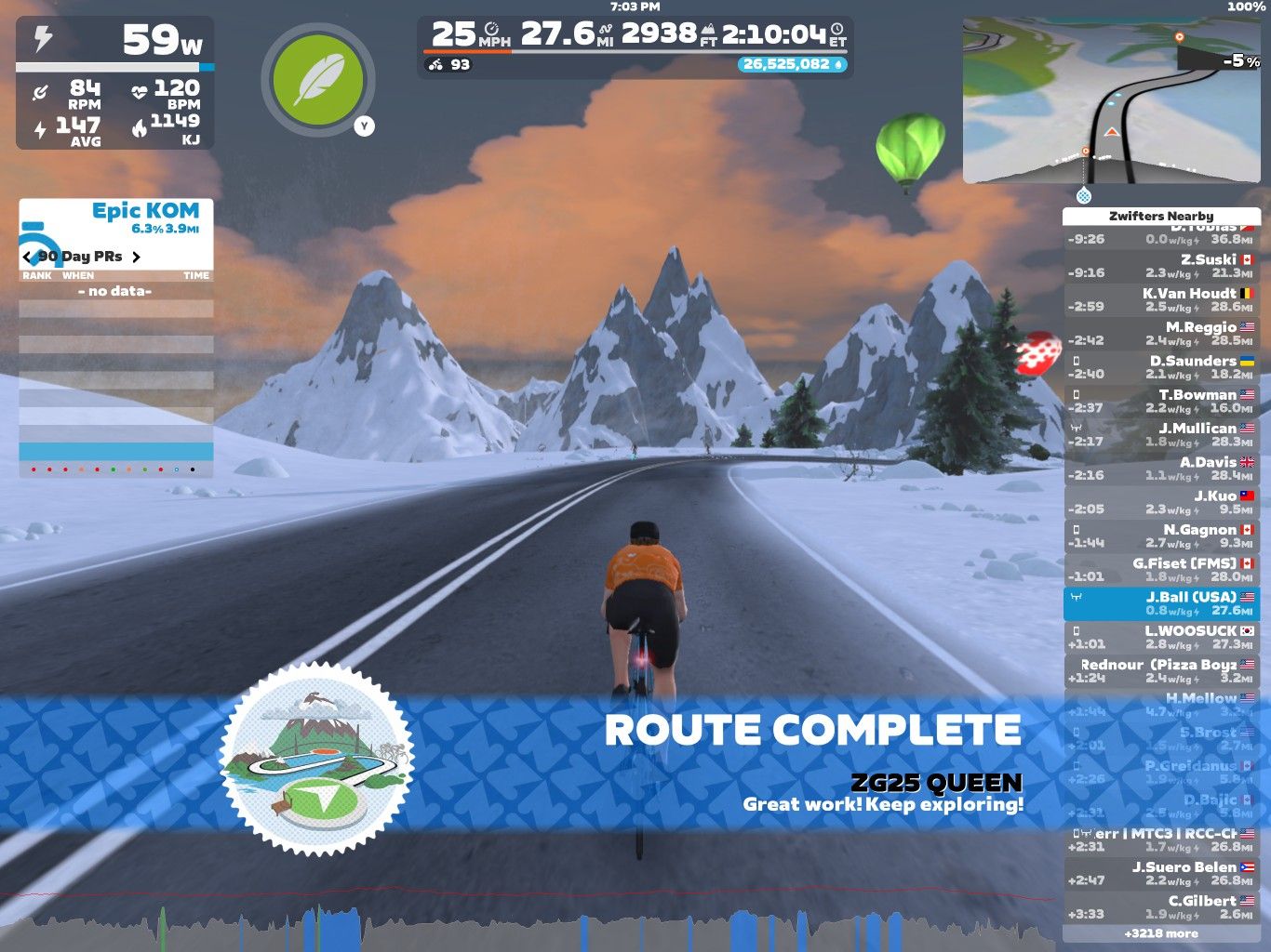 A cyclist in a virtual landscape on Zwift rides along a snowy road with mountains in the background. The screen shows cycling stats, including power, speed, distance, and heart rate, along with a message that says