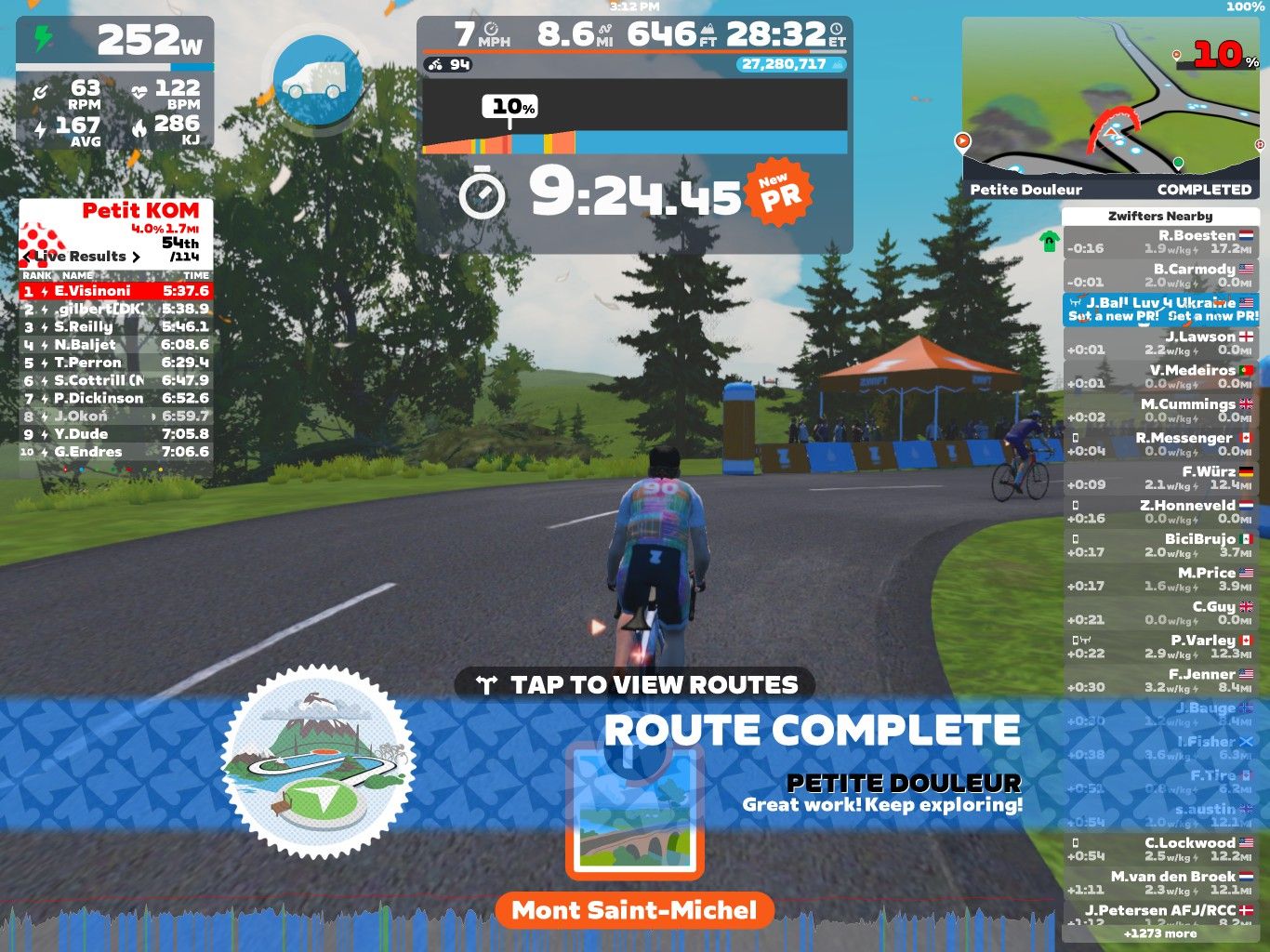 A screenshot from Zwift showing a virtual cycling scene. The display includes the cyclist's performance metrics and rankings in a race segment called