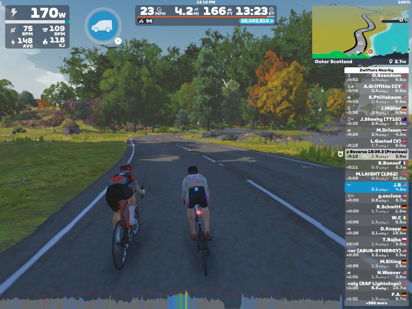 Two cyclists ride side by side on a virtual road in Zwift, surrounded by colorful trees and greenery. The on-screen display shows their speed, power output, and metrics such as heart rate and distance covered. A map in the corner indicates their location in Outer Scotland.