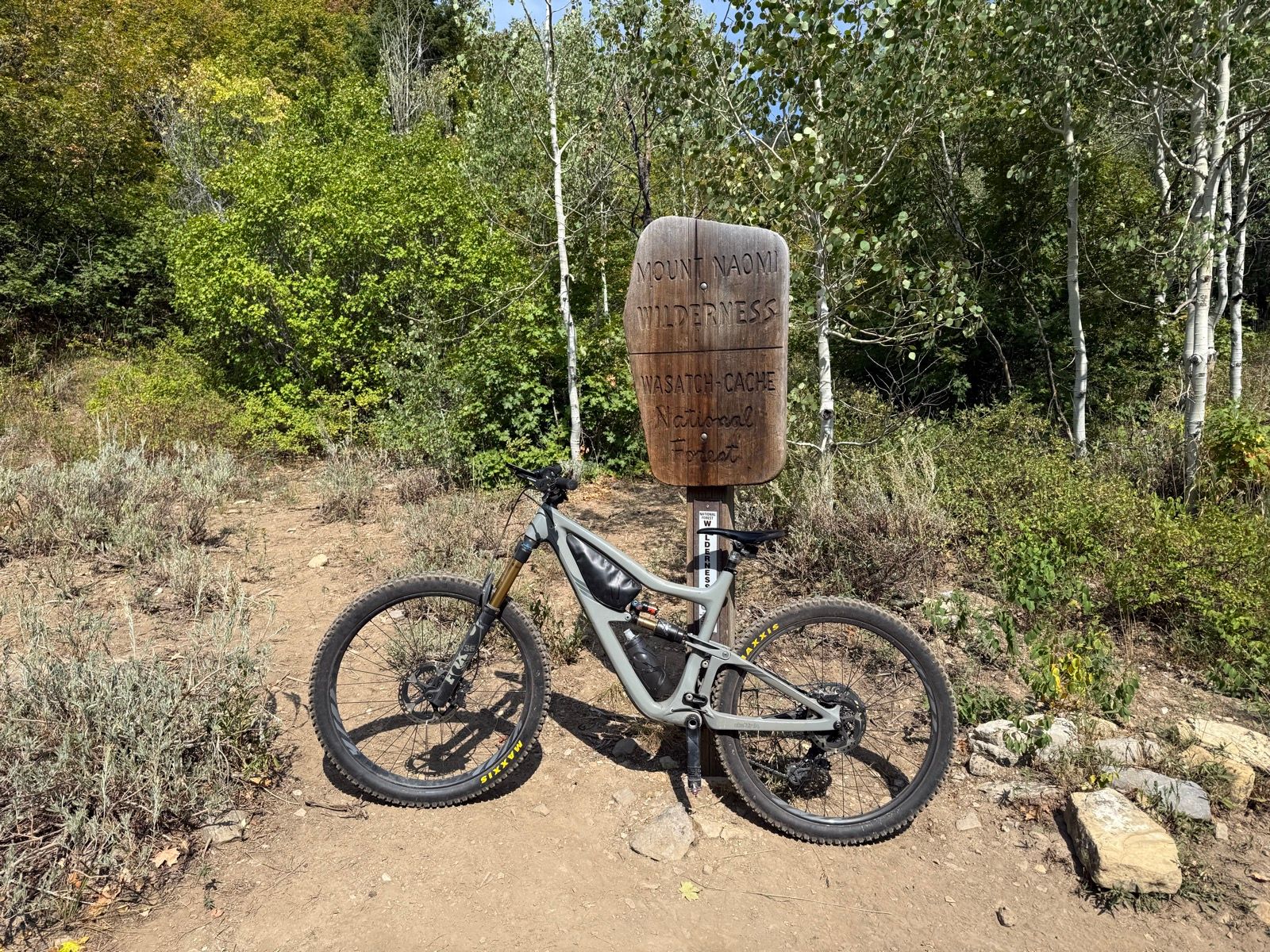 A mountain bike is standing next to a wooden sign that reads 