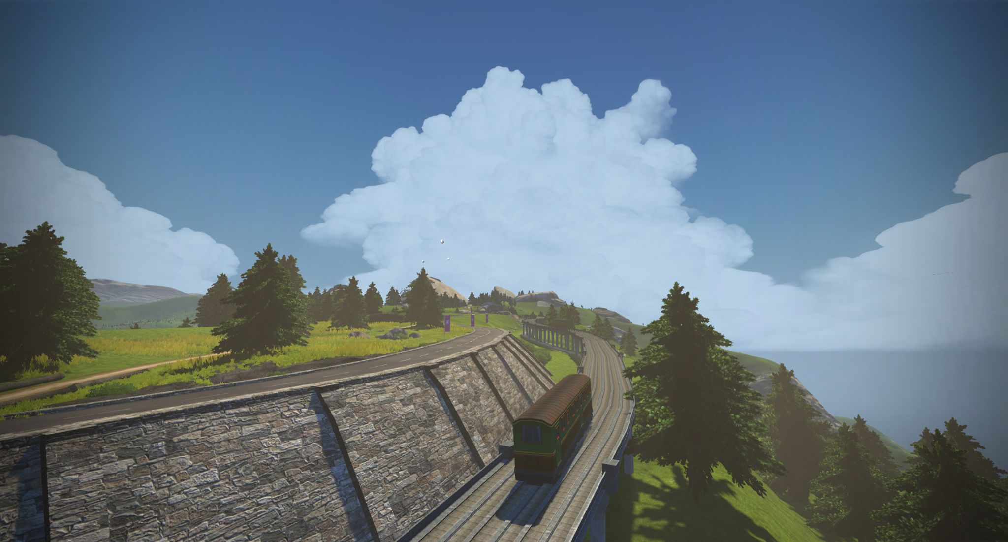 A scenic view featuring a winding railway track that runs alongside a grassy landscape dotted with trees, under a bright blue sky with fluffy white clouds in the background.