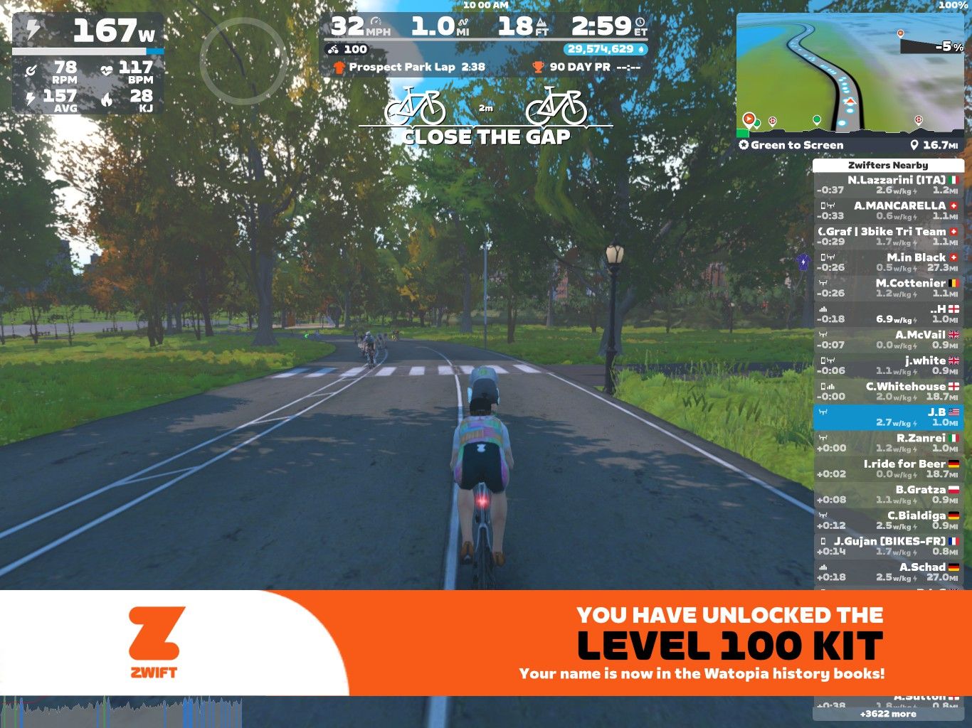 A cyclist is riding on a virtual road in Zwift, with trees lining the path and a scoreboard displaying various metrics such as speed, power, and heart rate. The overlay indicates that the user has unlocked the 