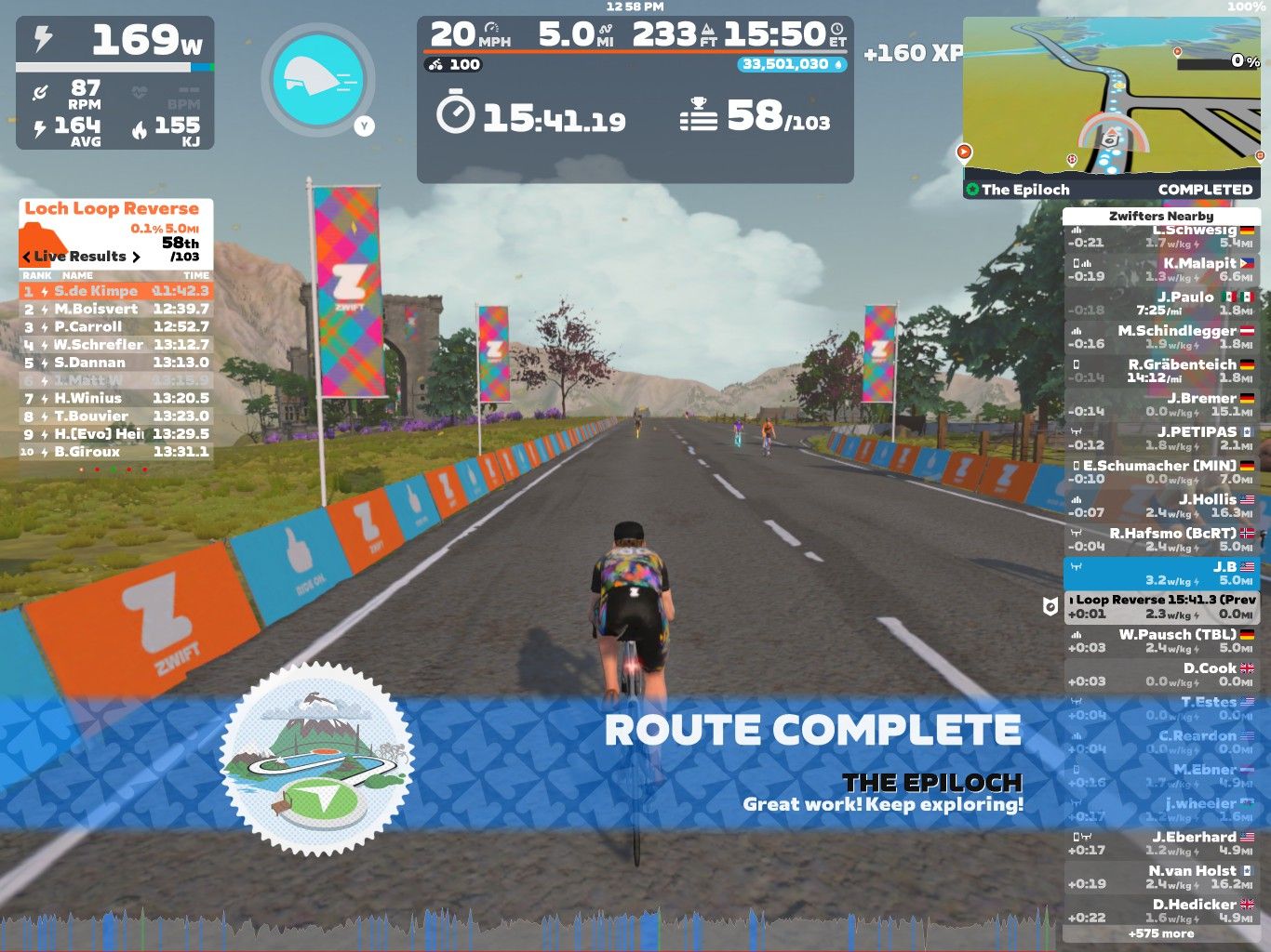 A cyclist is riding on a virtual road in Zwift, celebrating the completion of the 